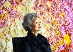 Adrienne Clarkson sitting against wall of flowers 