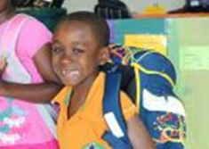 Young boy smiling with backpack filled with supplies