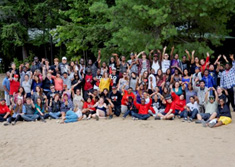Large group youth on beach with hands raised